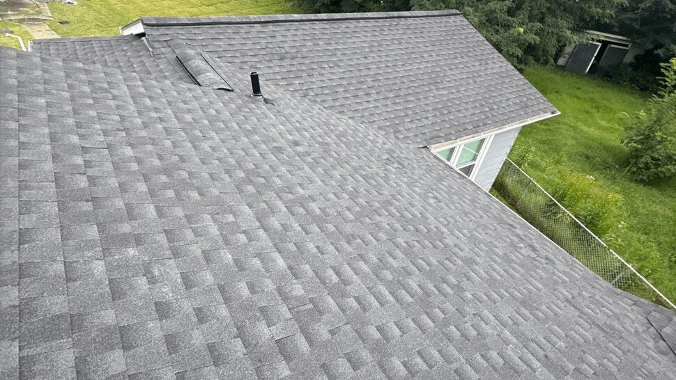 Aerial shingle roof view with valley | Wells Home Improvements Aerial view of gray shingle roof showing valley, vents and backyard