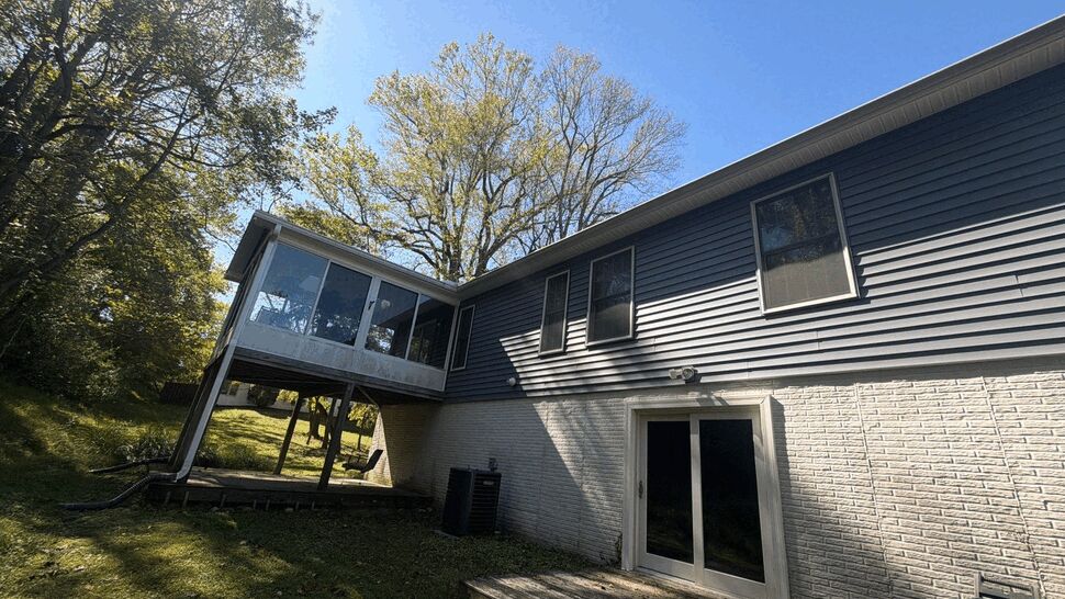 Rear Home Siding and Screened Porch | Wells Home Improvements Gray-sided home with screened porch, windows, and rear entry door.