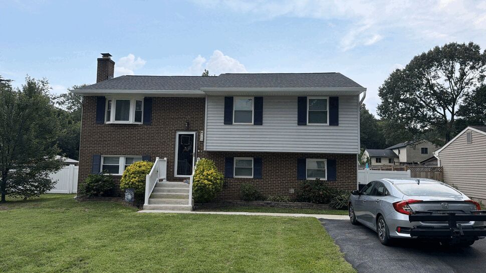 Front view of split-level brick and siding home with lawn and driveway