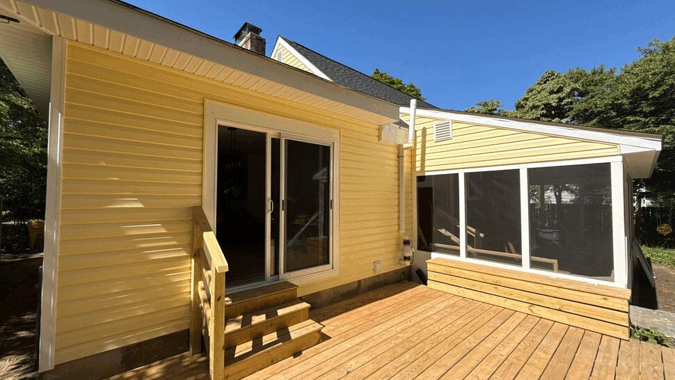 Yellow house back deck with sliding door, small stairs and screened porch