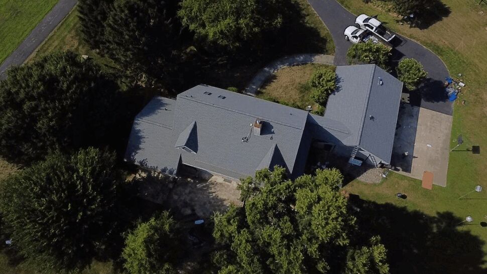 Top-down Roof Inspection | Wells Home Improvements Top-down drone view of a shingled roof and surrounding trees.