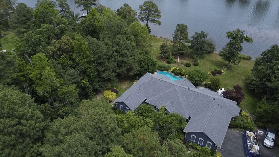 Tree-Lined Home Roofing | Wells Home Improvements Aerial view of a large gray roof surrounded by trees and a pool.