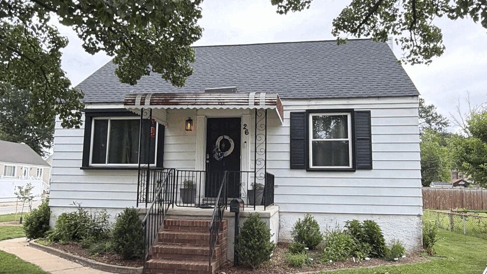 Front view of white bungalow with black shutters, fresh siding and shingled roof